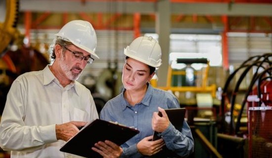 Responsable qualité et technicienne en casque consultant un document d'audit dans un atelier de production
